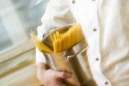 Chef hurrying through kitchen with spaghetti in pan