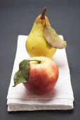 Red apple and pear with leaves on cloth