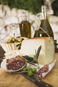 Käse, Salami, Oliven und Olivenöl auf Tisch im Freien