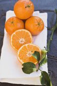 Whole and half clementines on white cloth, with leaves