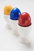 Three coloured eggs in egg cups