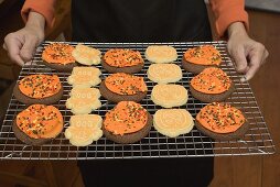 Hands holding Halloween biscuits on cake rack