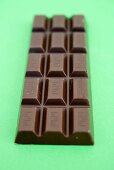 Bar of chocolate on green background