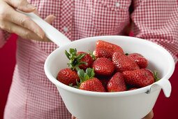 Woman holding strainer full of strawberries