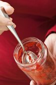 Woman holding almost empty jar of strawberry jam