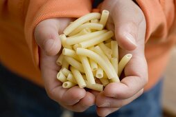 Child's hands holding macaroni