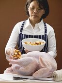 Woman stuffing turkey with bread cubes