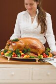 Young woman holding roast turkey on large platter