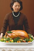 Woman holding stuffed roast turkey on large platter