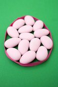 Pink sugared almonds on green background
