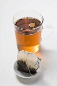 Earl Grey tea in glass cup, tea bag in foreground