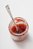Marmeladenglas mit Löffel und Resten von Erdbeermarmelade