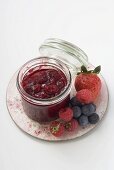Jar of berry jam and fresh berries on plate