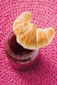 Croissant auf einem Glas Himbeermarmelade (Draufsicht)