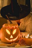 Woman in witch's hat holding pumpkin lantern