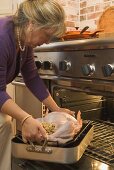 Woman putting stuffed turkey into the oven