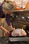 Woman putting stuffed turkey into the oven