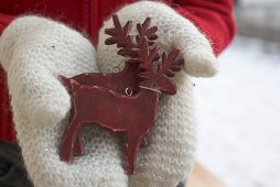 Hände in Handschuhen halten zwei Rentiere (Weihnachtsdeko)
