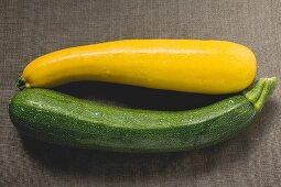 Yellow and green courgettes on brown fabric background