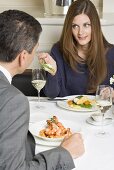 Frau reicht Mann Gabel mit Spargel im Restaurant