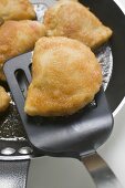 Breaded pasties in frying pan with spatula
