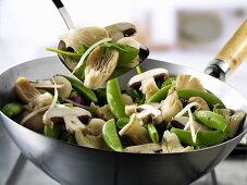 Vegetables and mushrooms in wok and on spatula