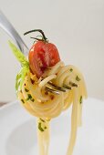 Spaghetti mit Kirschtomate auf Gabel über weißem Teller