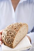 Woman holding sunflower bread (part of a loaf)