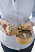 Woman holding three wholesome bread rolls