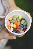 Child's hands holding tub of coloured sugar eggs