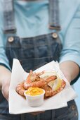 Woman holding tiger prawns with dip on napkin