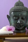 Orchid & soap on white towel beside statue of Buddha