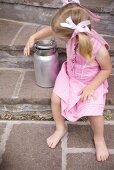 Small girl with milk can on stone steps