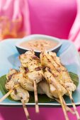 Woman holding platter of satay and peanut dip