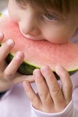 Child biting into watermelon