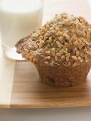 Muffin topped with chopped nuts, glass of milk