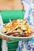 Woman holding a plate of grilled vegetables