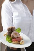 Woman serving pork fillet, tomatoes & basil on toast