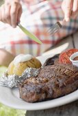 Woman eating grilled steak with baked potato