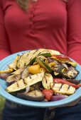 Woman holding a plate of grilled vegetables