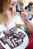 Männerhand reicht Frau ein Brownie beim Gartenfest