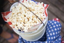 Hand holding wooden bucket full of popcorn (4th of July, USA)