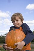 Boy holding a large pumpkin in a field