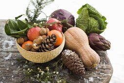 Stillleben mit Äpfeln, Gemüse, Nüssen und Zapfen auf Holztisch