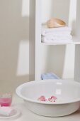 Wash bowl with flowers, soap, towels and candle in glass