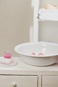 Wash bowl with flowers, soap, candle in glass in bathroom