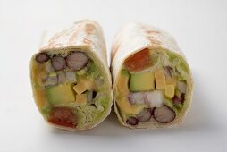 Two wraps filled with avocado, lettuce and cheese