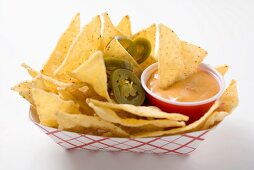 Nachos with chilli rings and dip in cardboard container