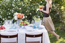Woman bringing iced tea to table laid in garden