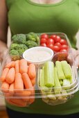 Woman holding plastic tray of vegetables and dip